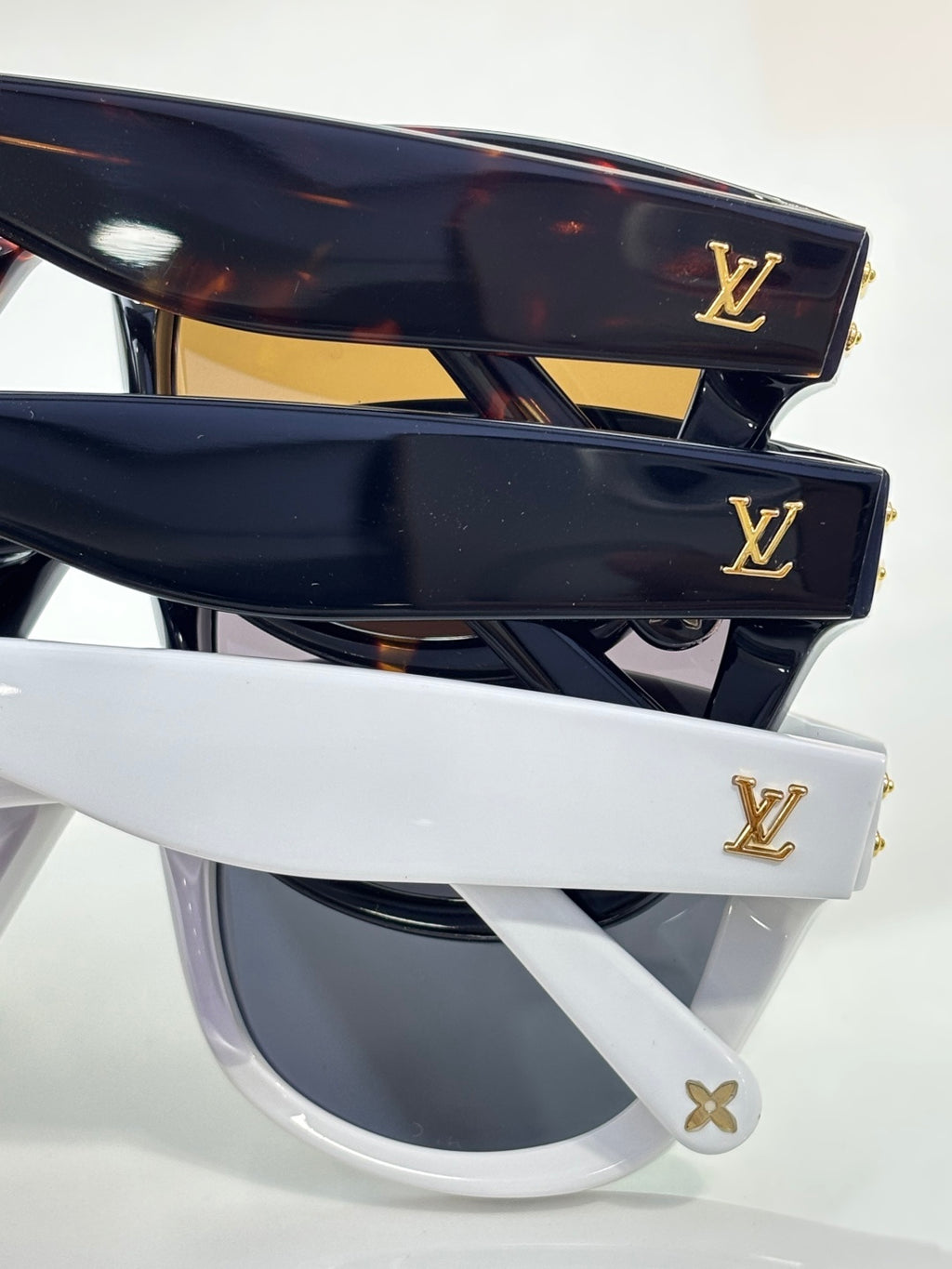 Louis Vuitton sunglasses with tortoiseshell and black frames, dark lenses, gold logos