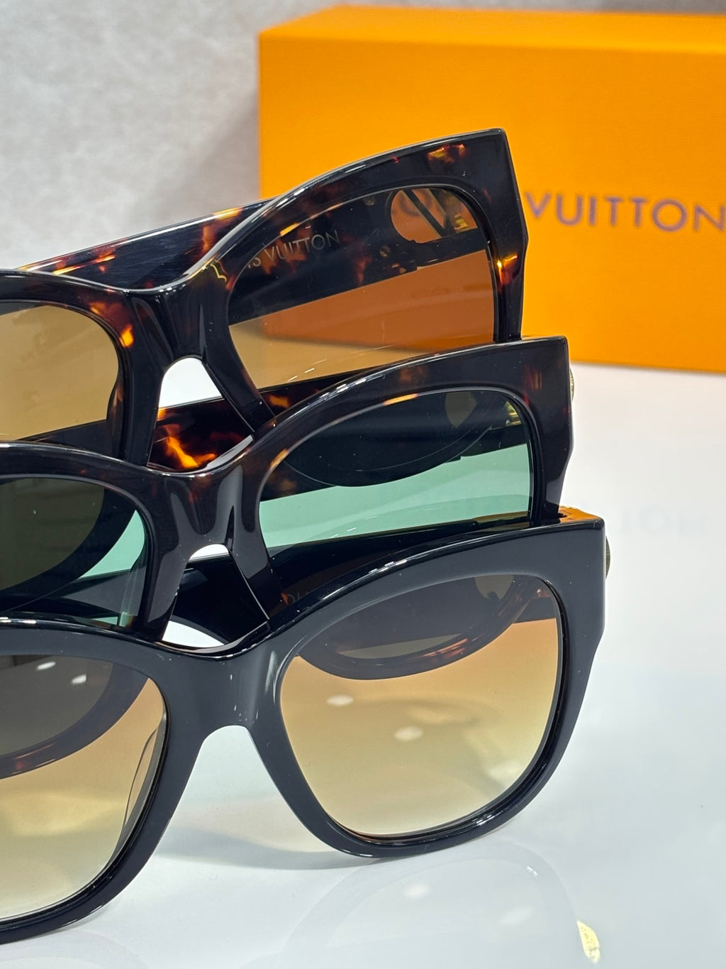 Stacked dark tortoiseshell sunglasses with green-blue and neutral lenses