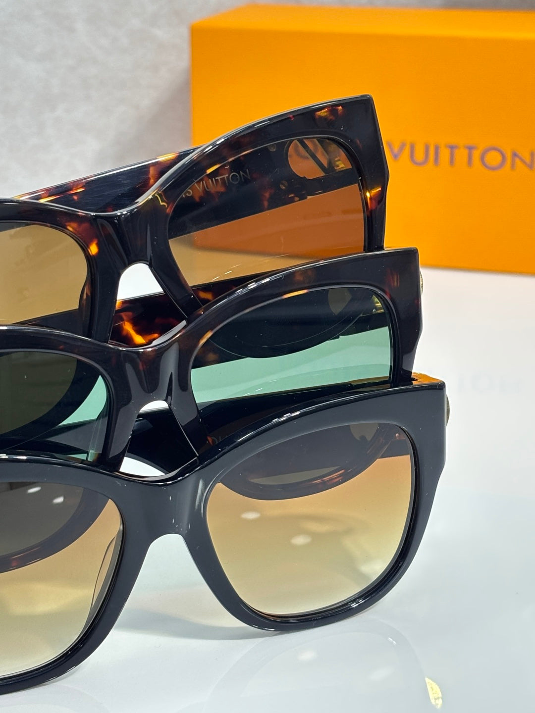 Stacked dark tortoiseshell sunglasses with green-blue and neutral lenses