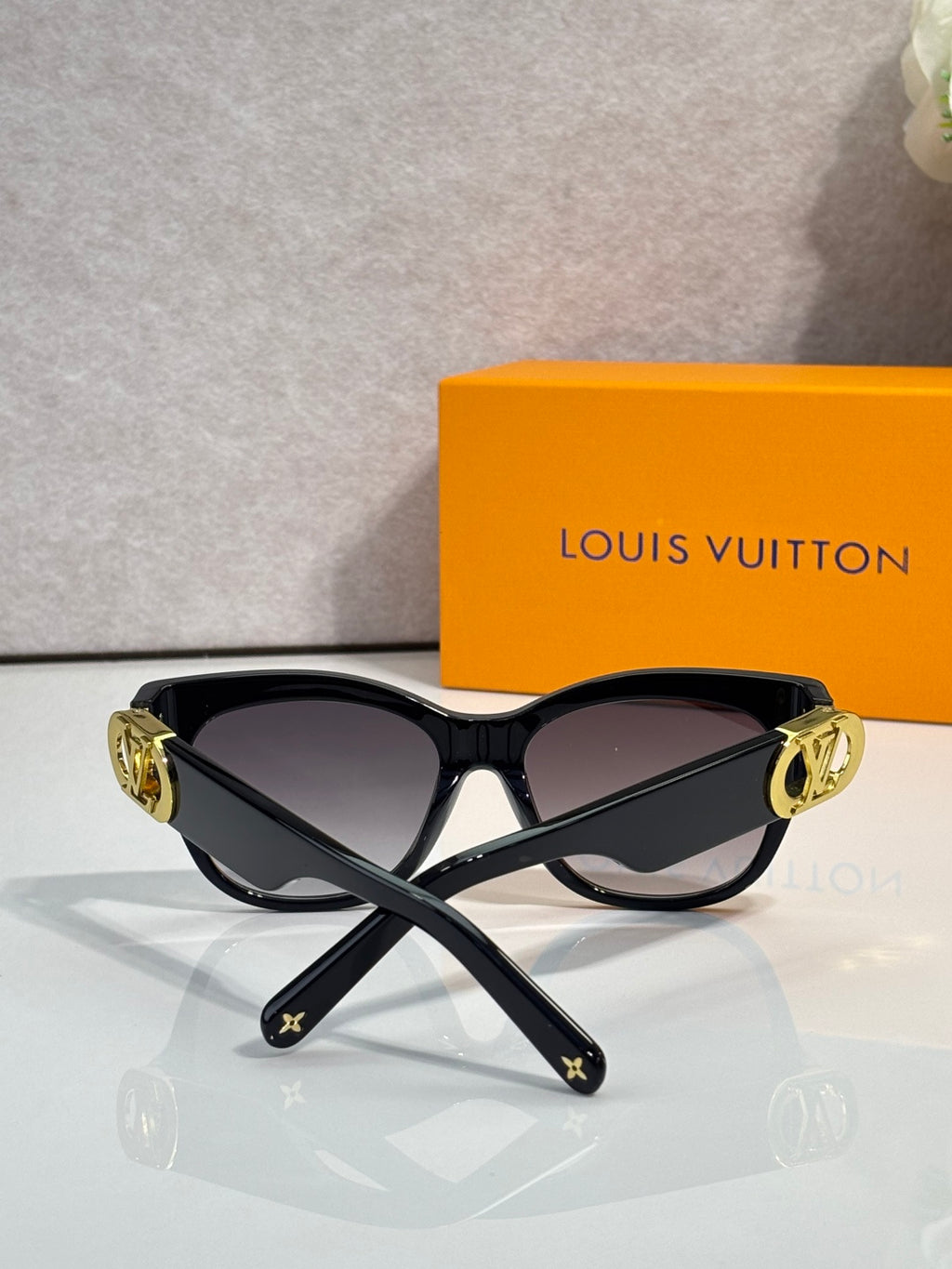 Dark sunglasses with gold LV-embossed arms and gradient lenses, angled view