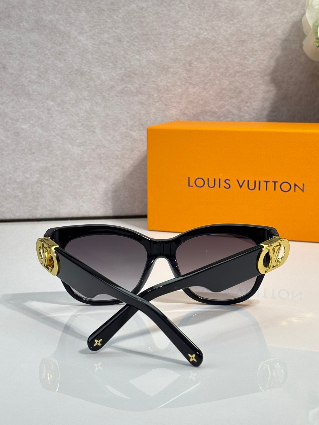 Dark sunglasses with gold LV-embossed arms and gradient lenses, angled view