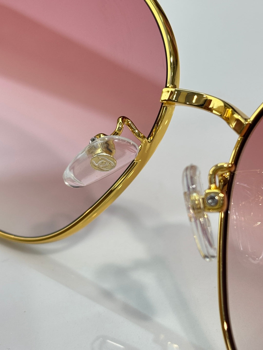 Sunglass frame detail with gold-tone arms and clear nose bridge