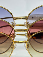 Sunglasses lens and frame close-up with gold-tone rims and colored tint
