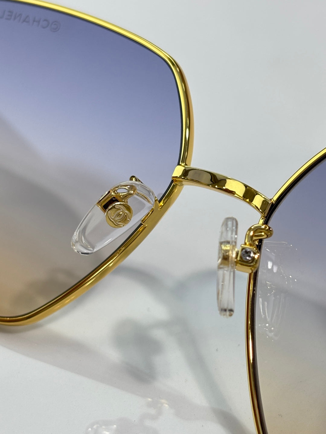 Gold-tone eyeglass frame close-up with clear hinge and lens support detail