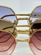 Gold-tone eyeglass frame close-up with stacked tinted lenses and metal bridge