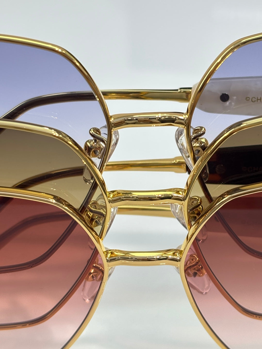 Gold-tone eyeglass frame close-up with stacked tinted lenses and metal bridge