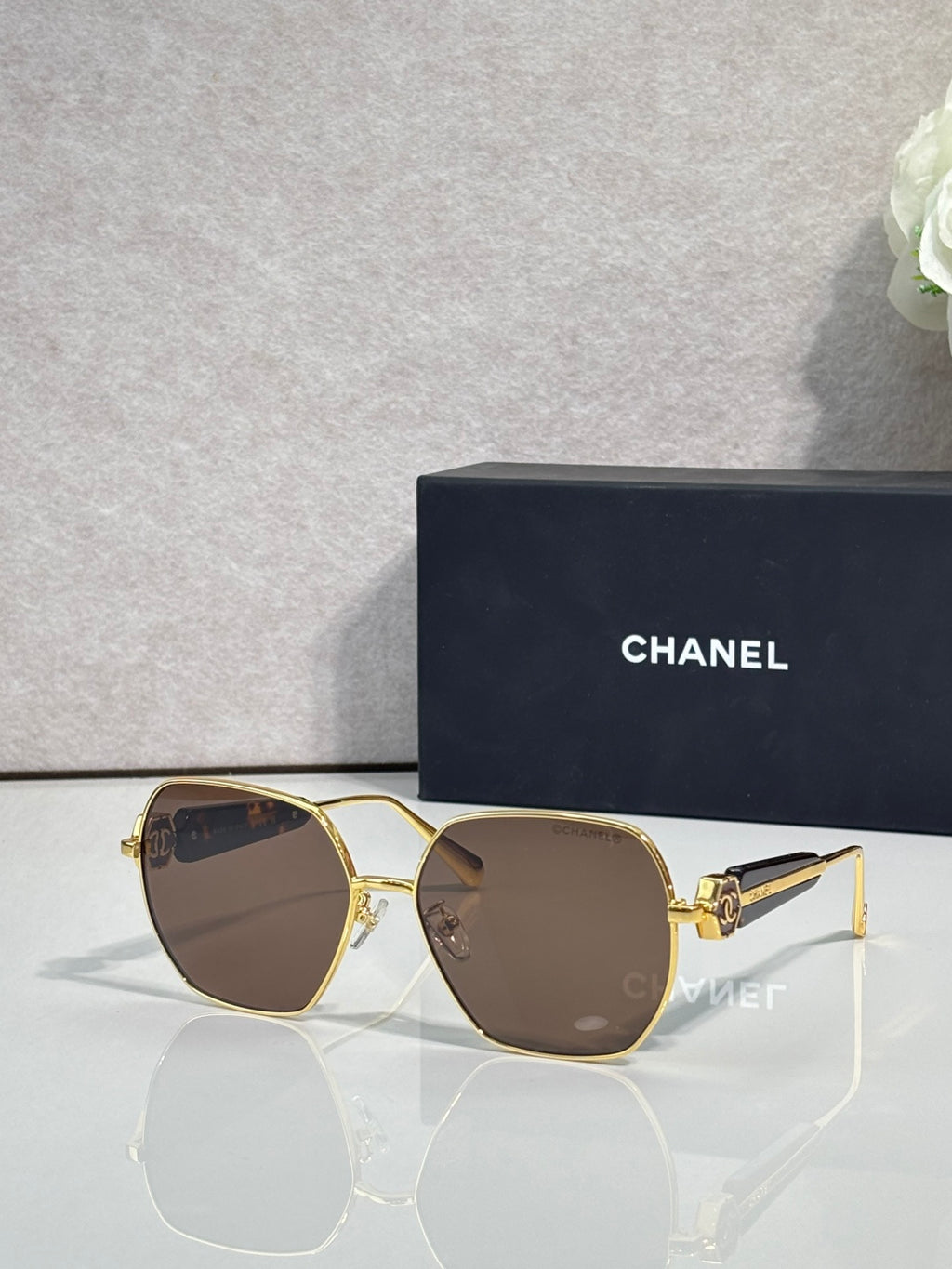 Gold-tone square sunglasses with brown lenses and emblem detail on temples