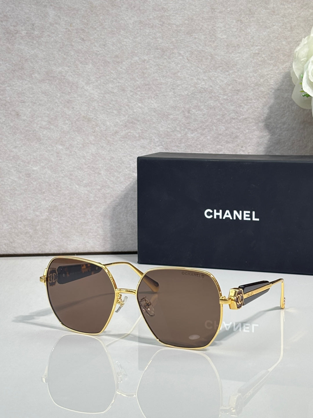 Gold-tone square sunglasses with brown lenses and emblem detail on temples