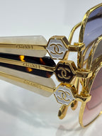 Gold-tone eyeglass frame close-up with engraved CHANEL temple accents and hinges