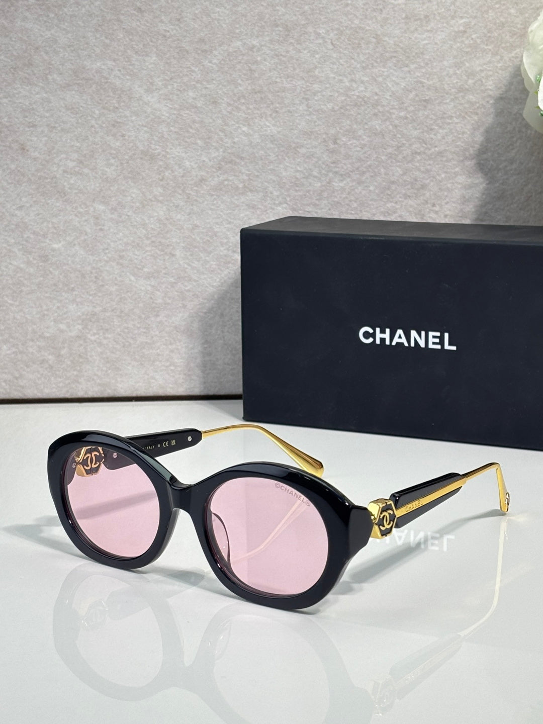 Chanel round sunglasses with black frames and pink tinted lenses, gold-tone accents