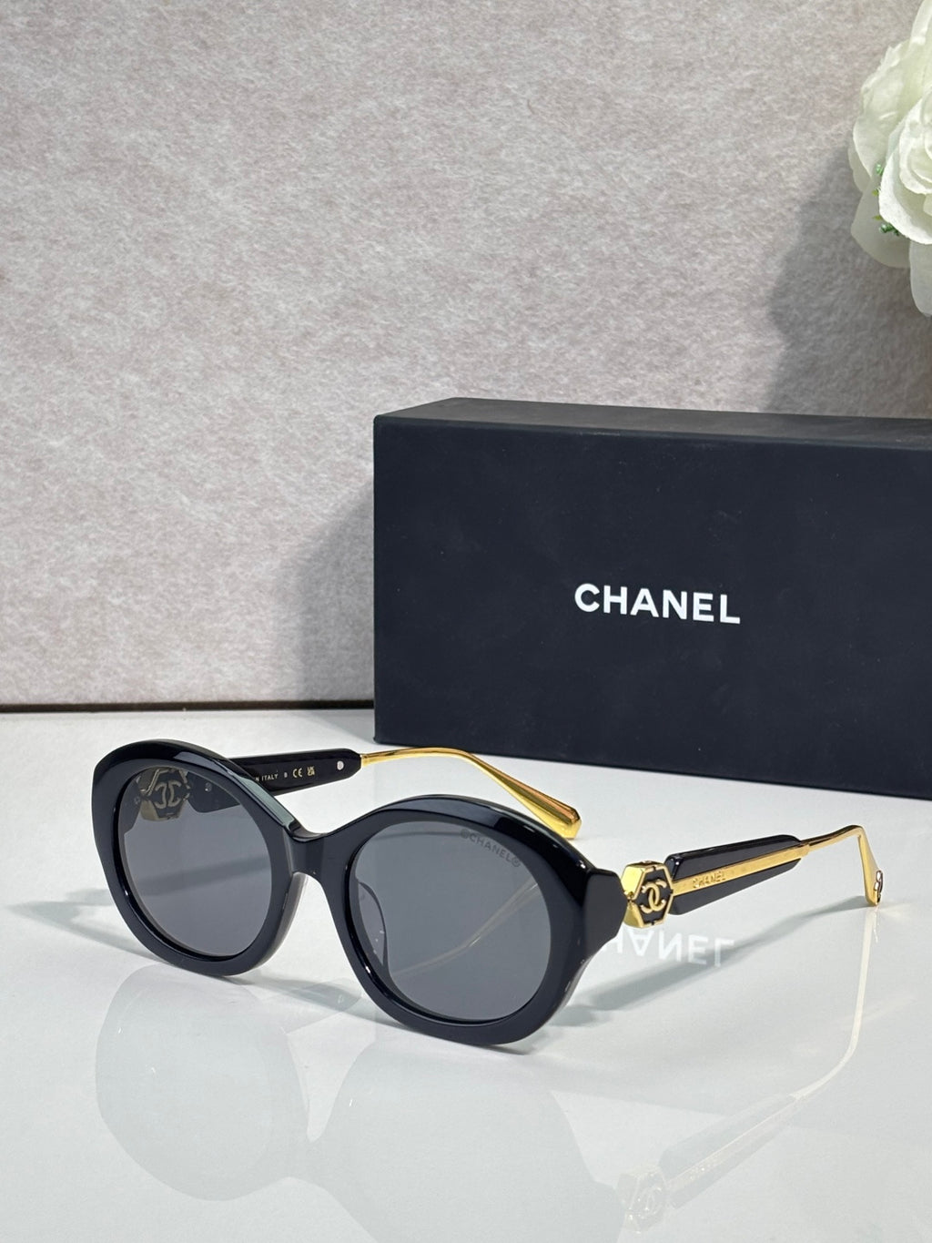 Chanel cat-eye sunglasses with black frames and dark gray tinted lenses, gold-tone details