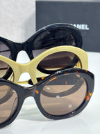 Chanel round sunglasses close-up with pale yellow and dark frames, tinted lenses