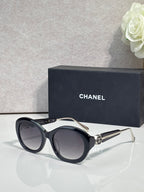 Chanel cat-eye sunglasses with black frames and dark lenses, gold-tone accents