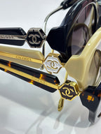 Chanel sunglasses close-up with gold-tone logo hardware on dark and yellow frames