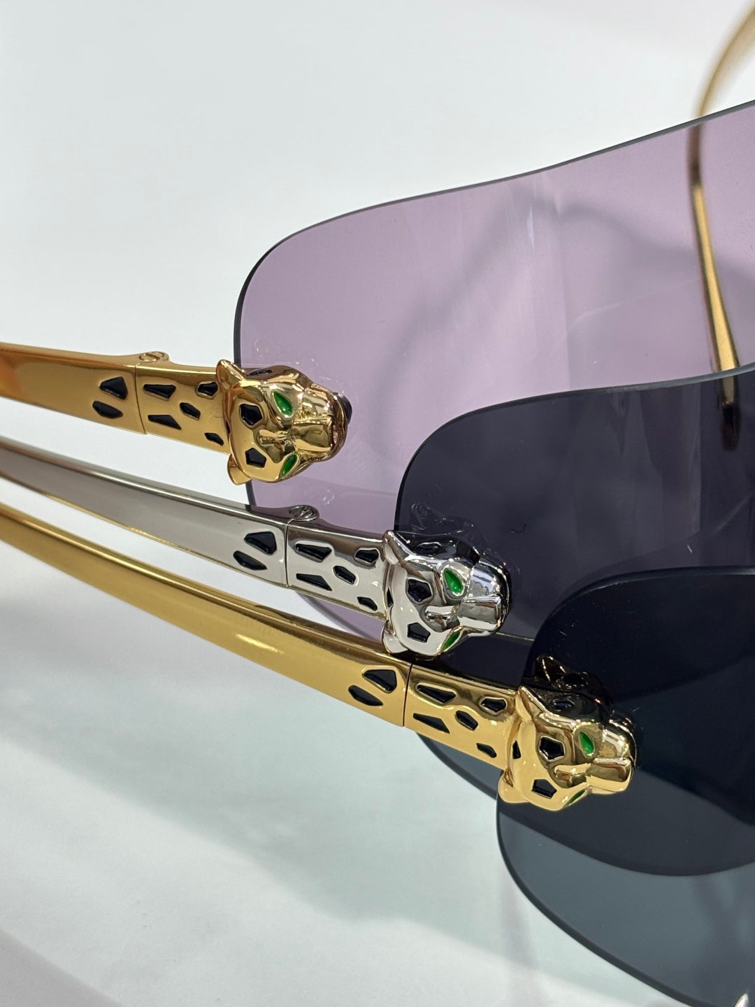 Cartier sunglasses close-up: gold hinges with green stone accents on dark arm