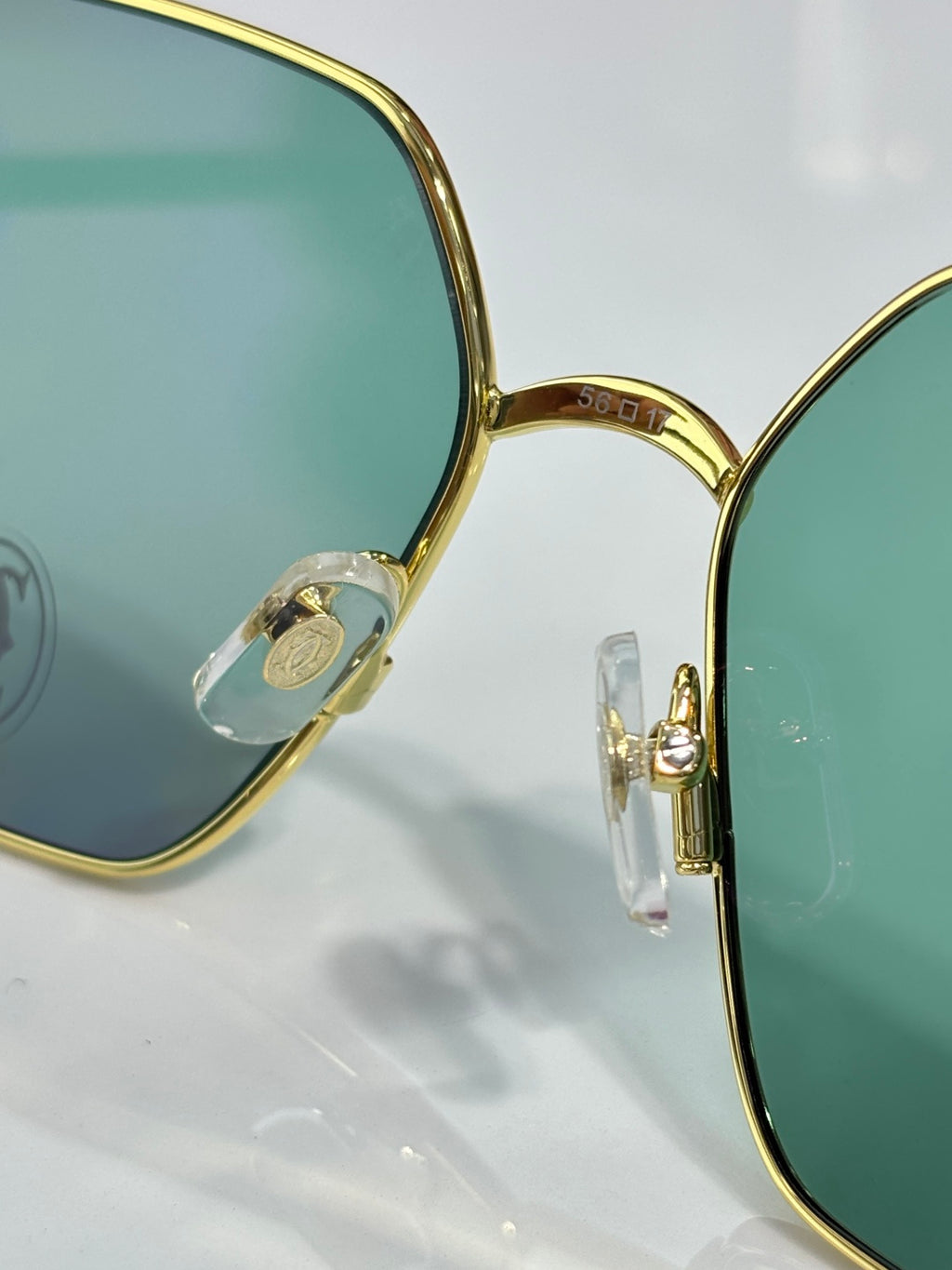 Gold rectangular sunglasses with green lenses, temple hinge detail close-up