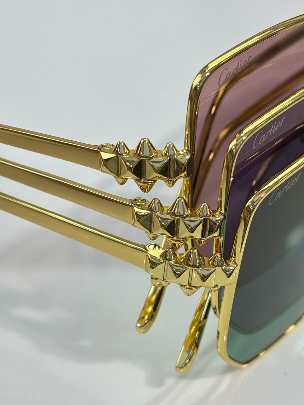 Gold sunglasses with decorative stud detailing on bridge, purple lens close-up