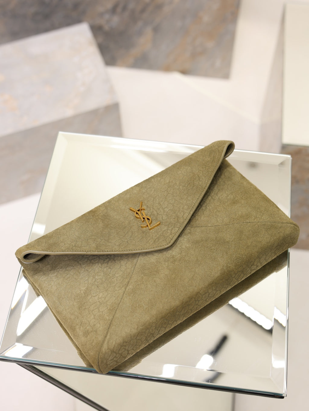 Olive textured leather envelope clutch bag with gold YSL logo on display