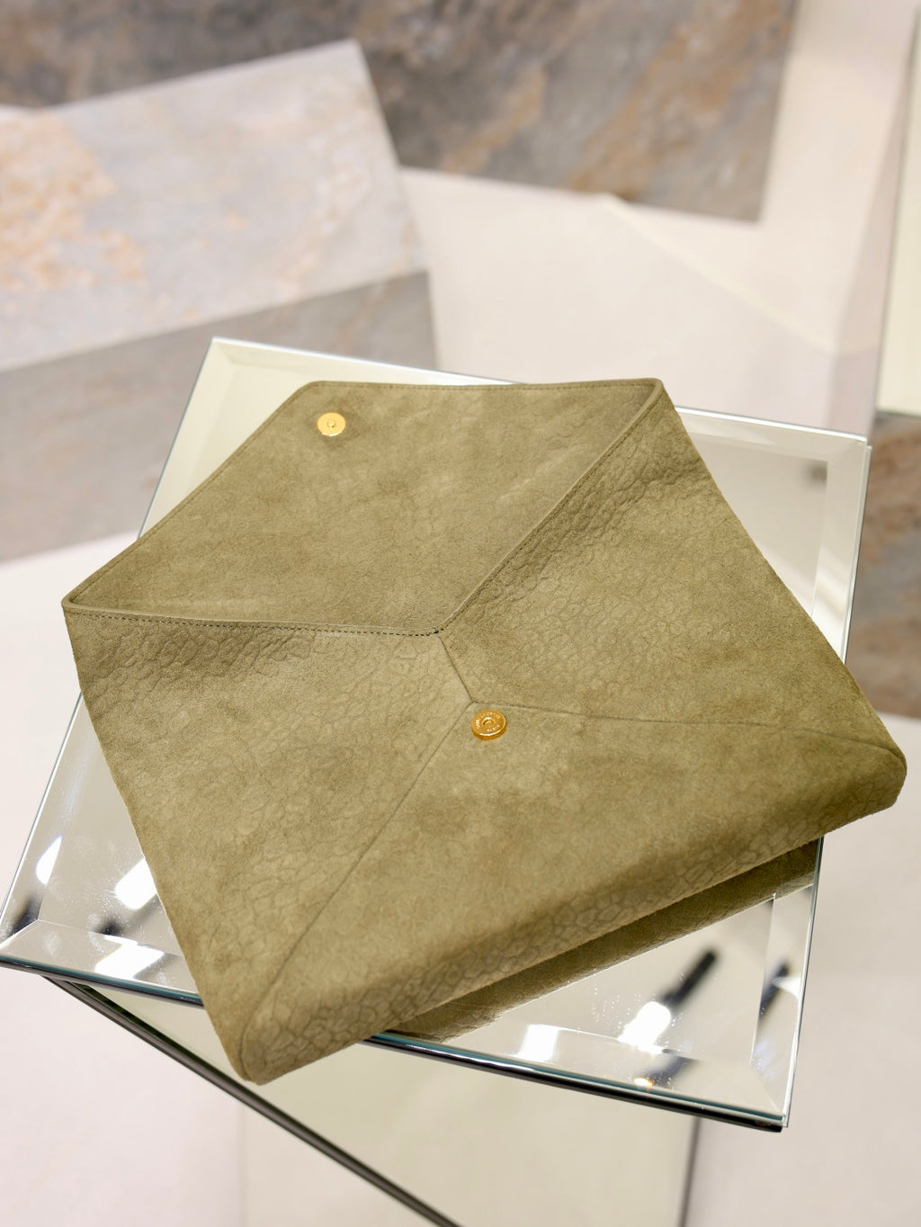 Olive textured leather clutch bag with circular gold snap on front panel
