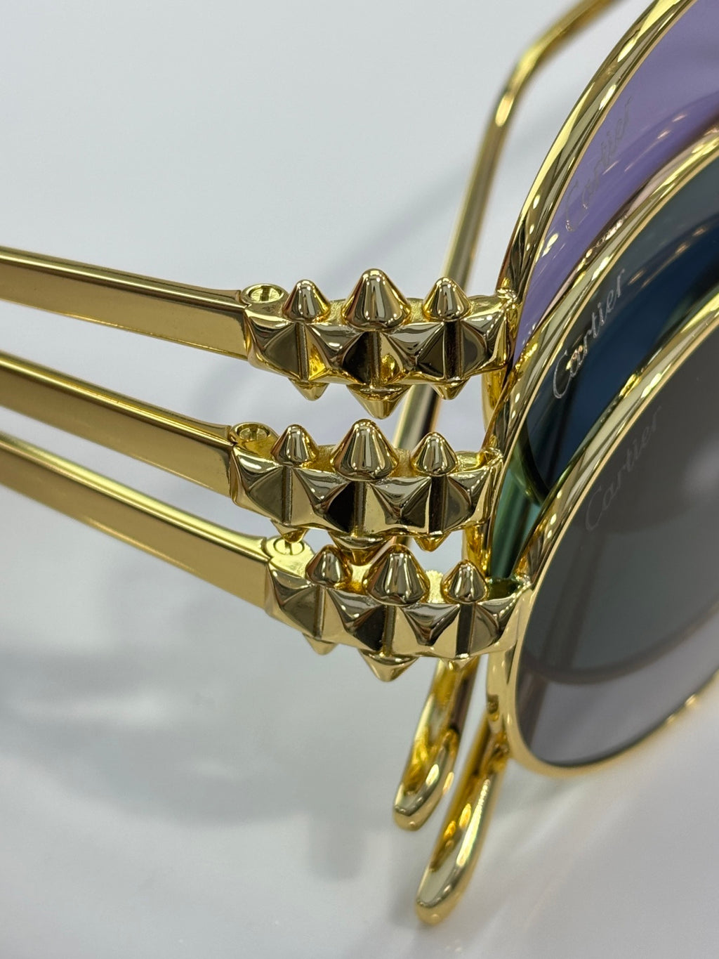 Close-up of gold temple detail on Cartier round glasses with dark lenses