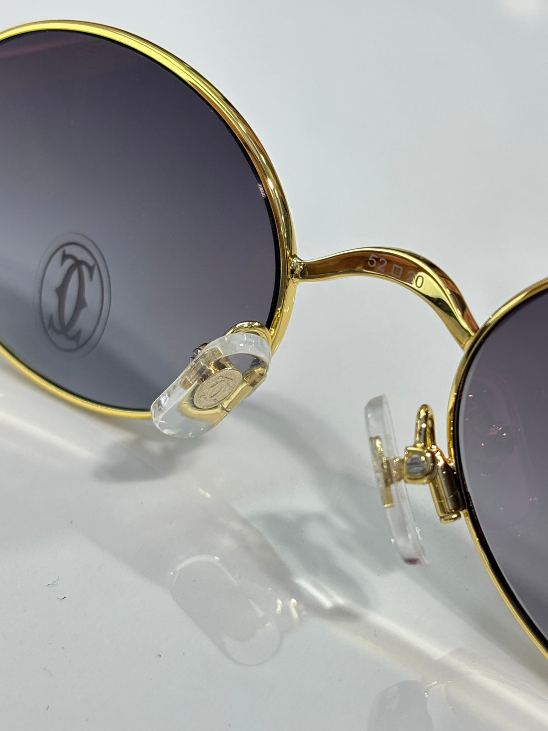 Close-up of Cartier round gold glasses with dark lenses and jeweled hinge