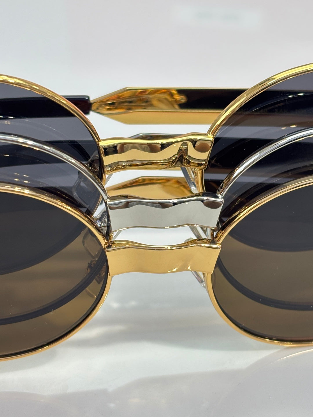 MiuMiu round sunglasses close-up of gold bridge and dark lenses