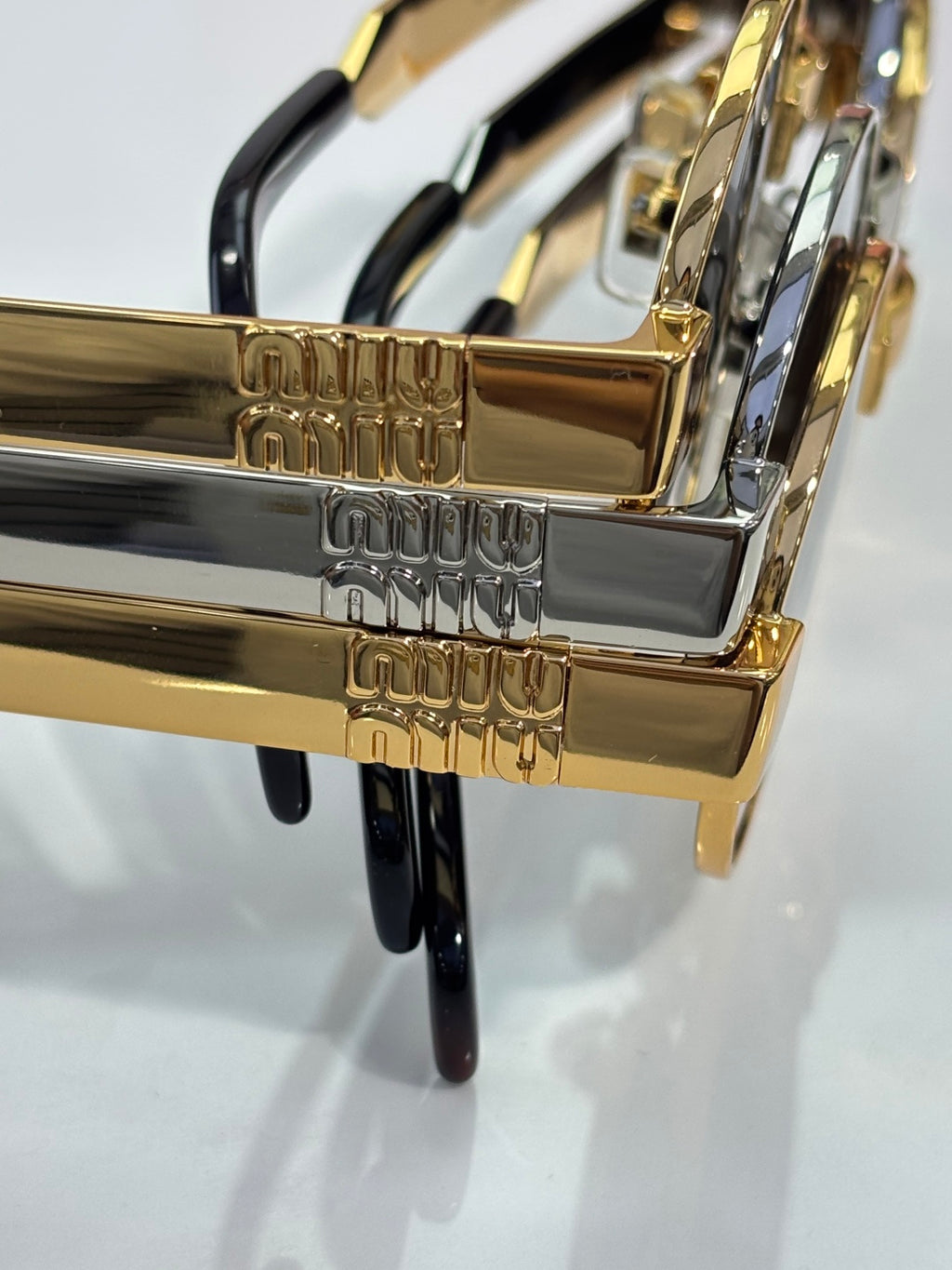 MiuMiu sunglasses close-up of gold-tone logo arms with black accents