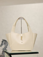 YSL cream tote bag with top handles and gold emblem clasp