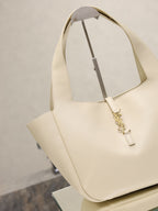 YSL cream tote bag with angled handles and gold emblem clasp
