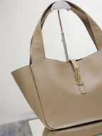 Beige leather tote bag angled view with gold YSL logo charm and open top