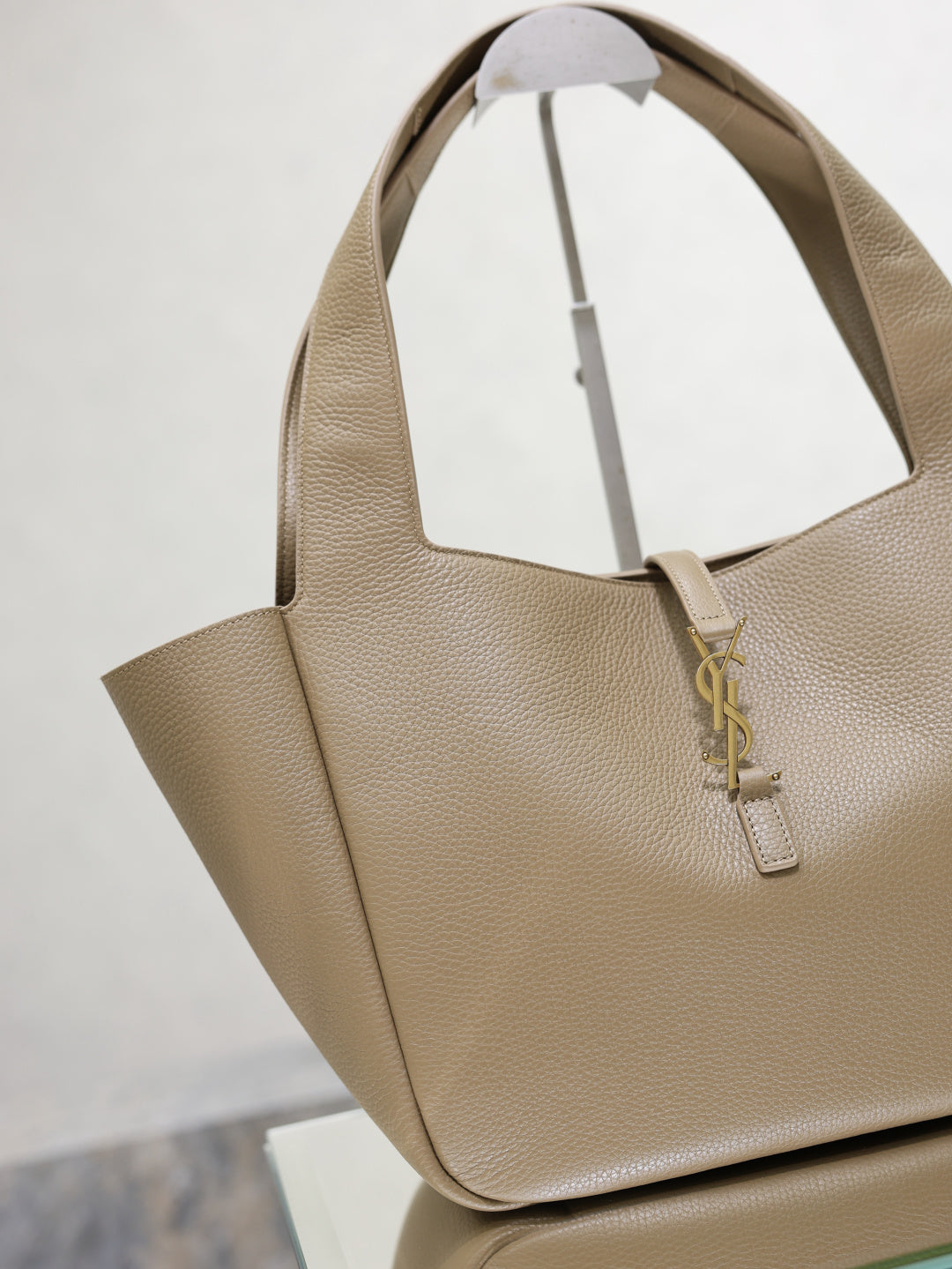 Beige leather tote bag angled view with gold YSL logo charm and open top