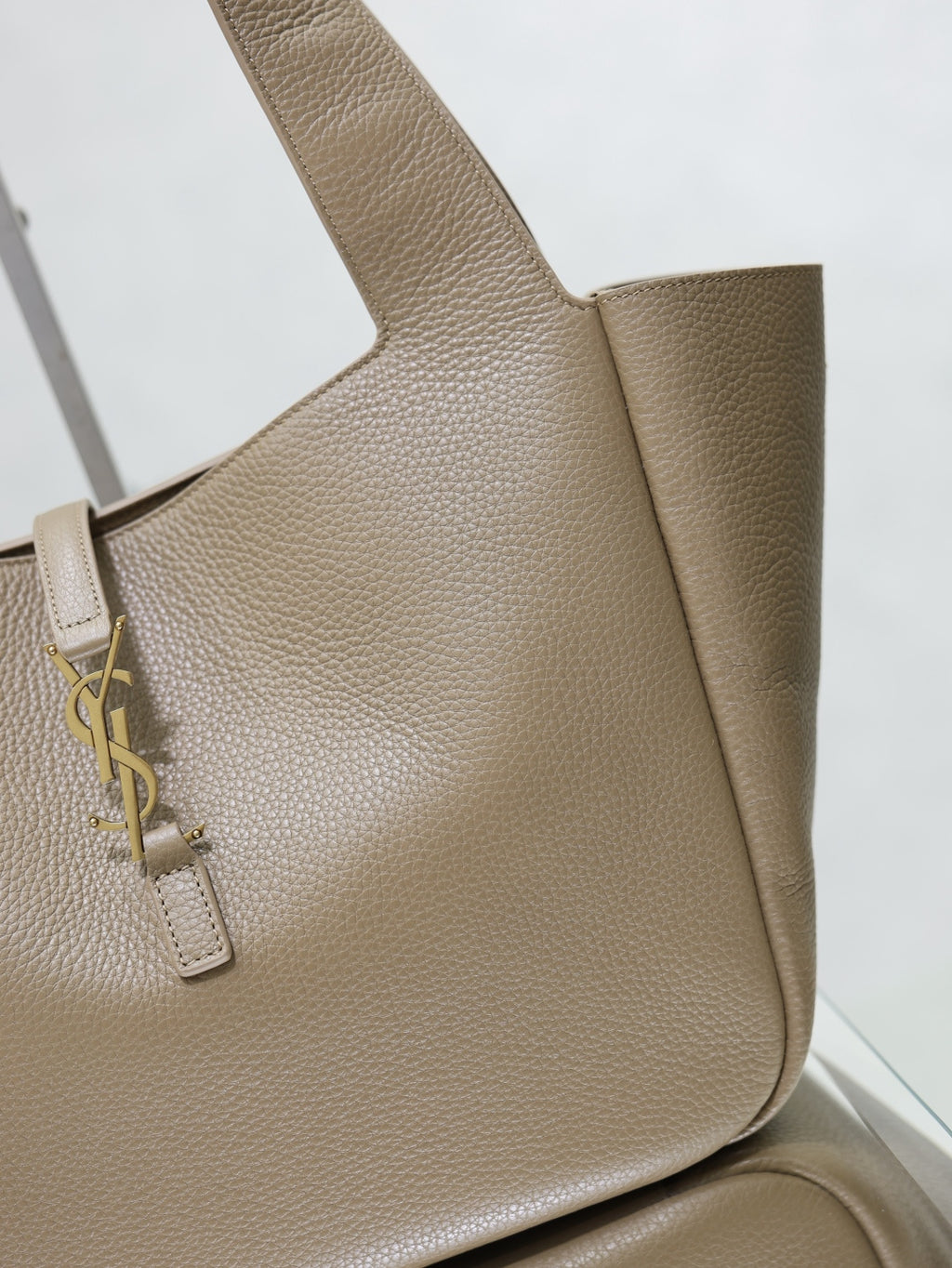 Beige leather YSL tote bag close-up of front panel and gold logo strap hardware