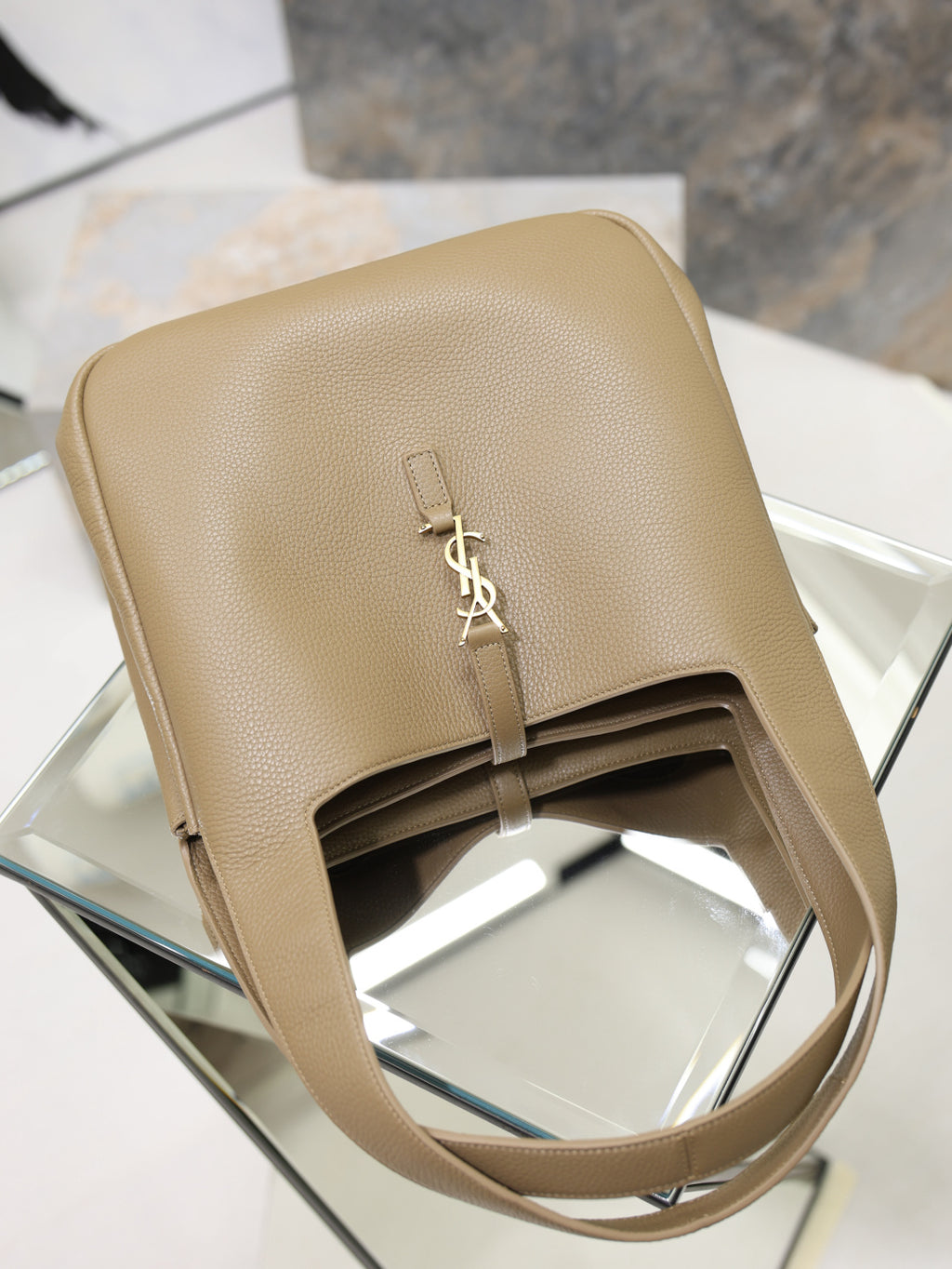 Beige leather YSL tote bag top view with gold logo plaque and front strap