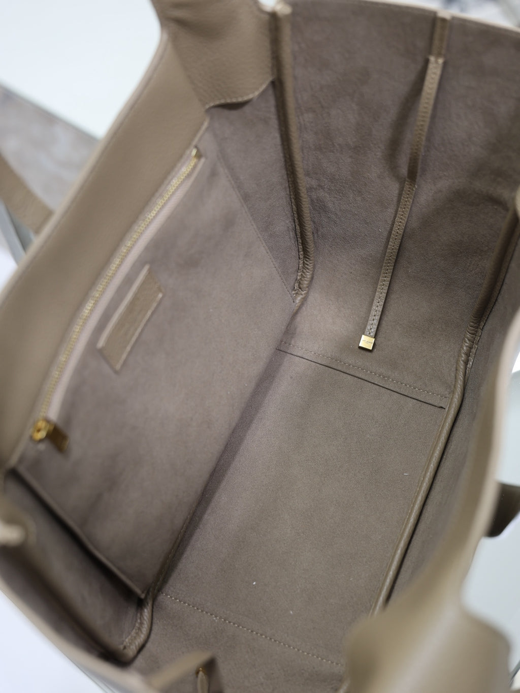 Beige leather tote bag interior with gray lining and zip pocket at center