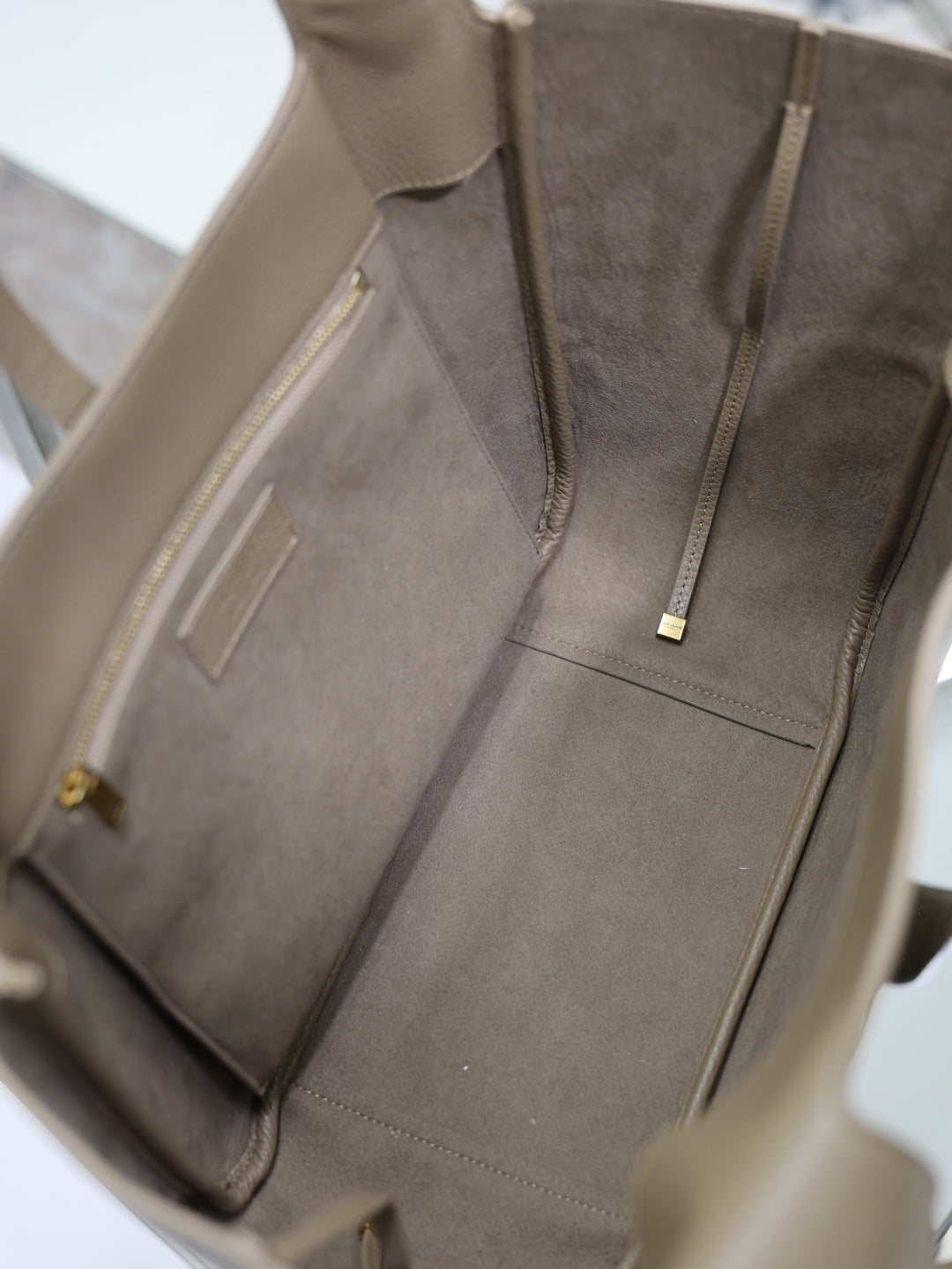 Beige leather tote bag interior with gray lining and zip pocket at center