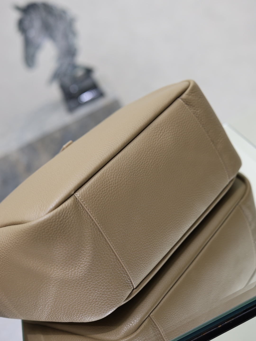 Beige leather tote bag close-up of folded edge seam and smooth textured surface