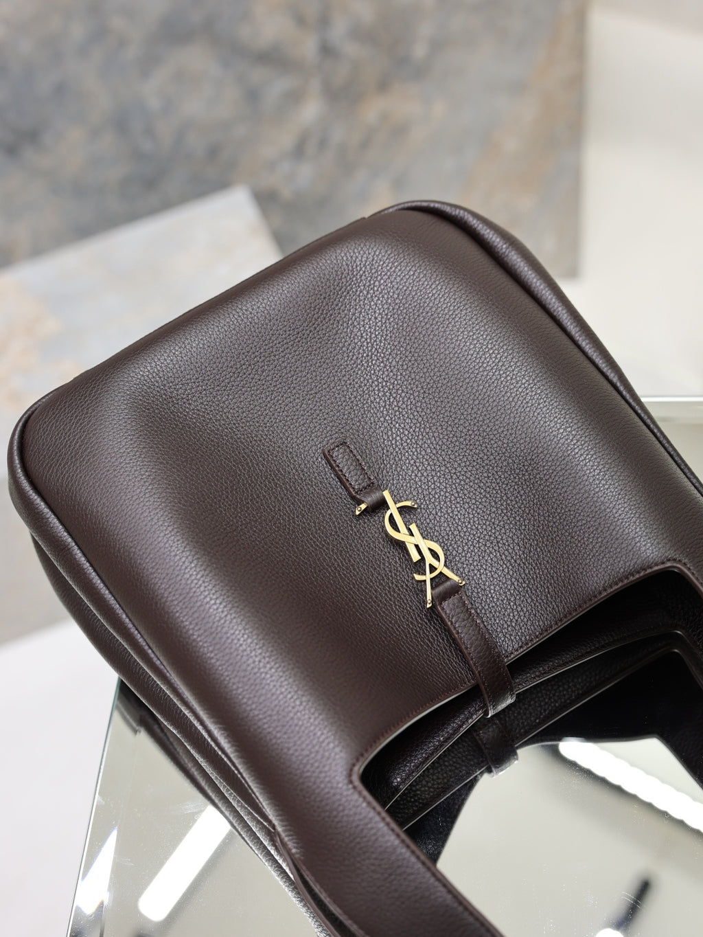 YSL bag top flap view in dark pebbled leather with gold YSL clasp