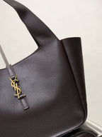 YSL bag side view in dark pebbled leather with gold YSL logo charm strap