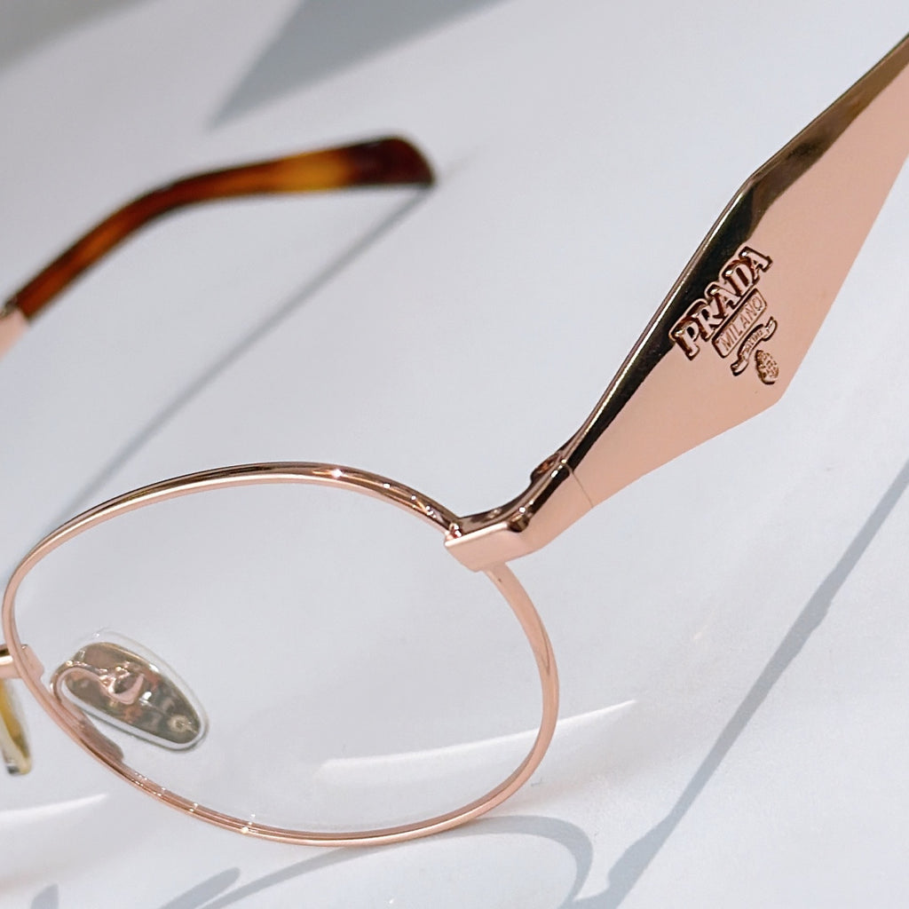 Prada eyeglasses close-up: gold round frame with logo temple arm