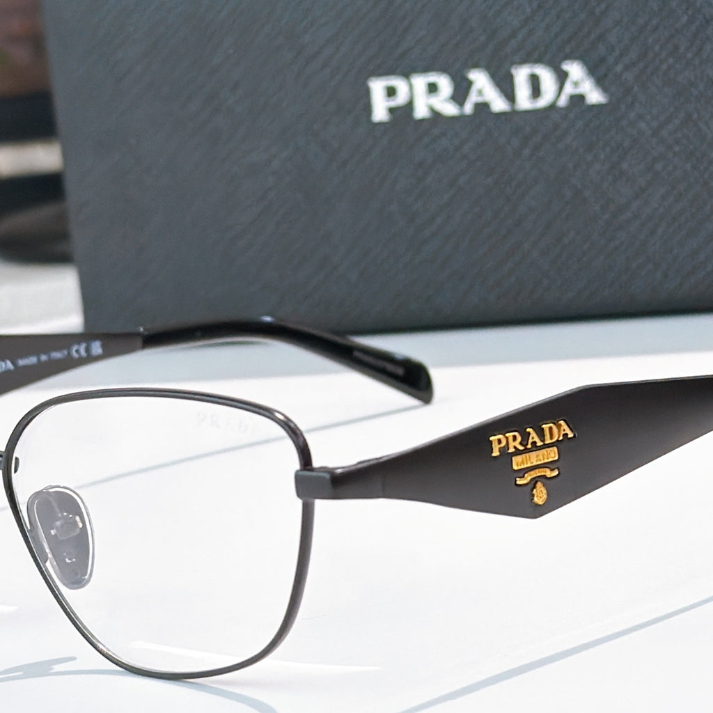 Prada eyeglasses close-up with black frame and gold logo on temple