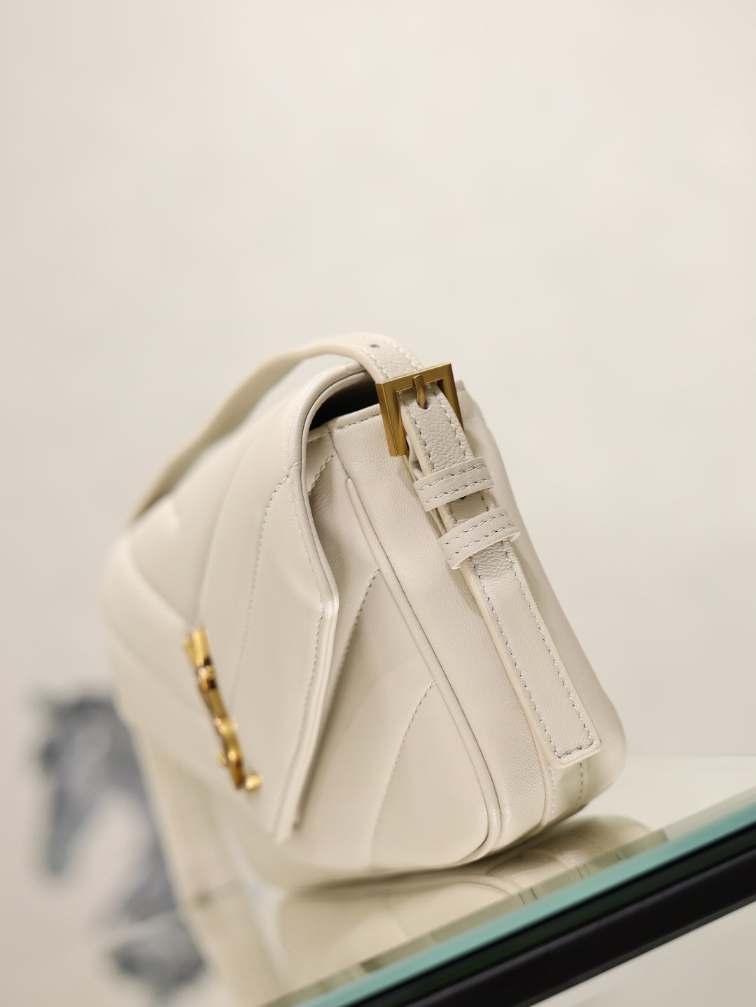 Cream YSL bag side view with top zipper pull and tassel strap