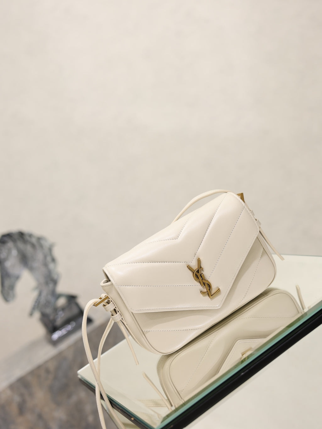 Cream quilted YSL shoulder bag angled view with gold-tone logo and tassel ties