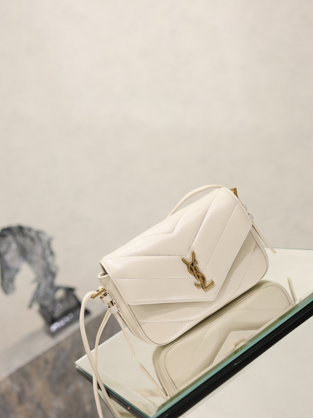 Cream quilted YSL shoulder bag angled view with gold-tone logo and tassel ties