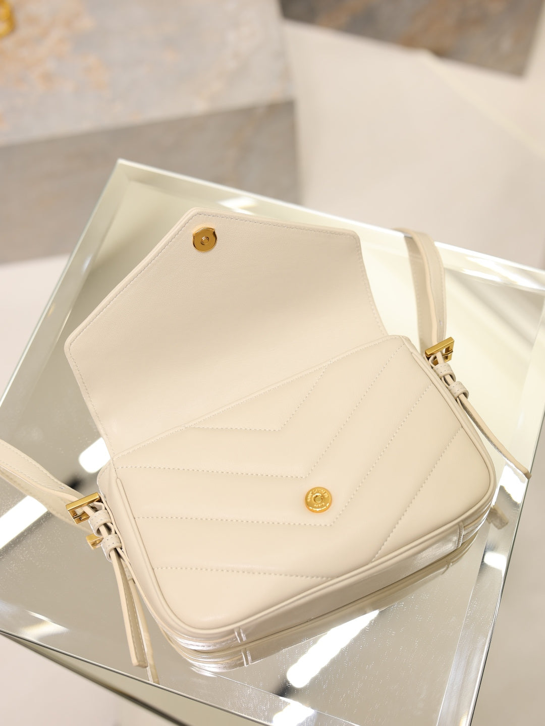 Cream YSL flap bag top view with snap button clasp and gold hardware