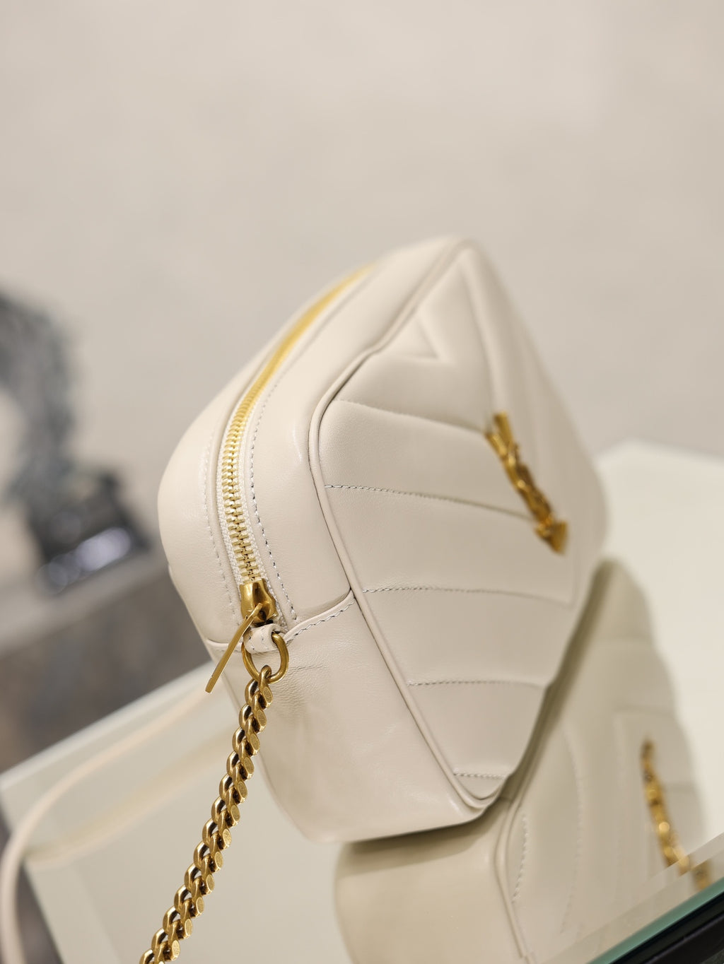 YSL cream quilted bag with gold chain strap and zip closure front view