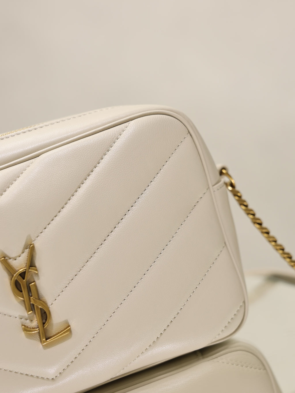 YSL cream quilted bag side profile with gold chain and logo clasp hardware