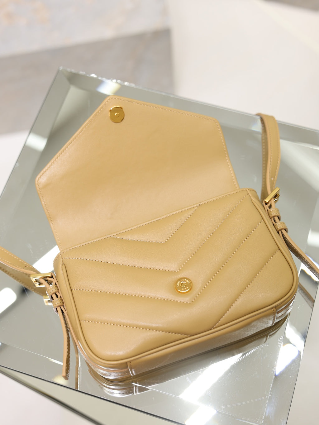 YSL beige quilted crossbody bag top view with open flap and gold logo stud