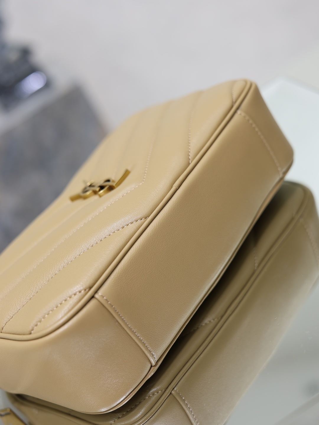 Close-up of quilted leather shoulder bag edge and zip pull with chain, light tan