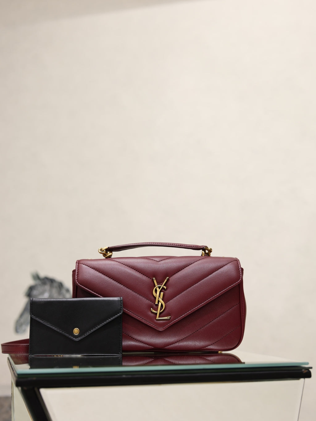Burgundy quilted shoulder bag with gold YSL logo on front flap, chain strap.