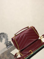 Burgundy quilted shoulder bag with front flap and gold chain strap on glass display.